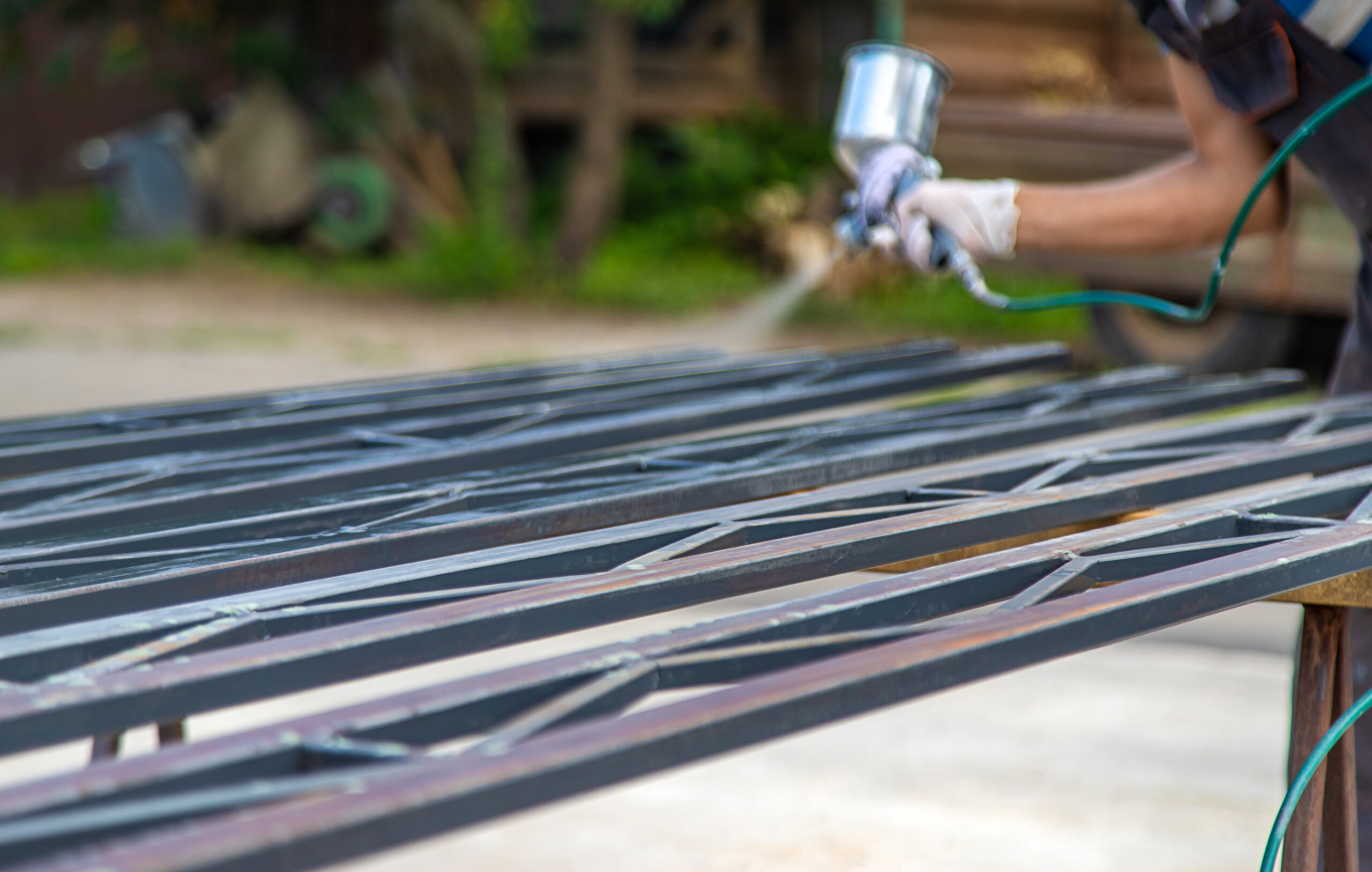 A man spray paints metal. Selective focus. work.
