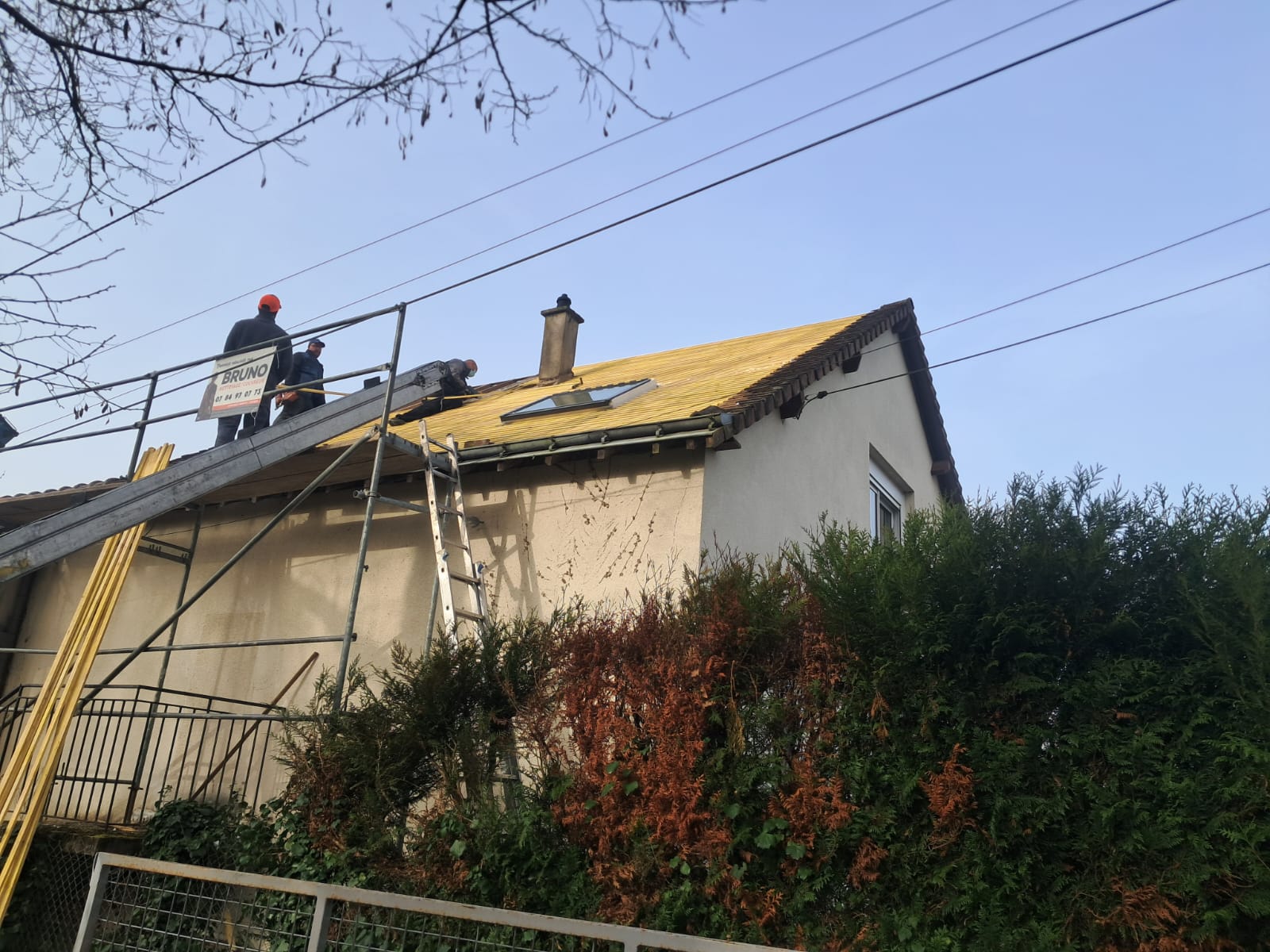 Équipe de couvreurs intervenant sur un chantier de rénovation de toiture avec échafaudage